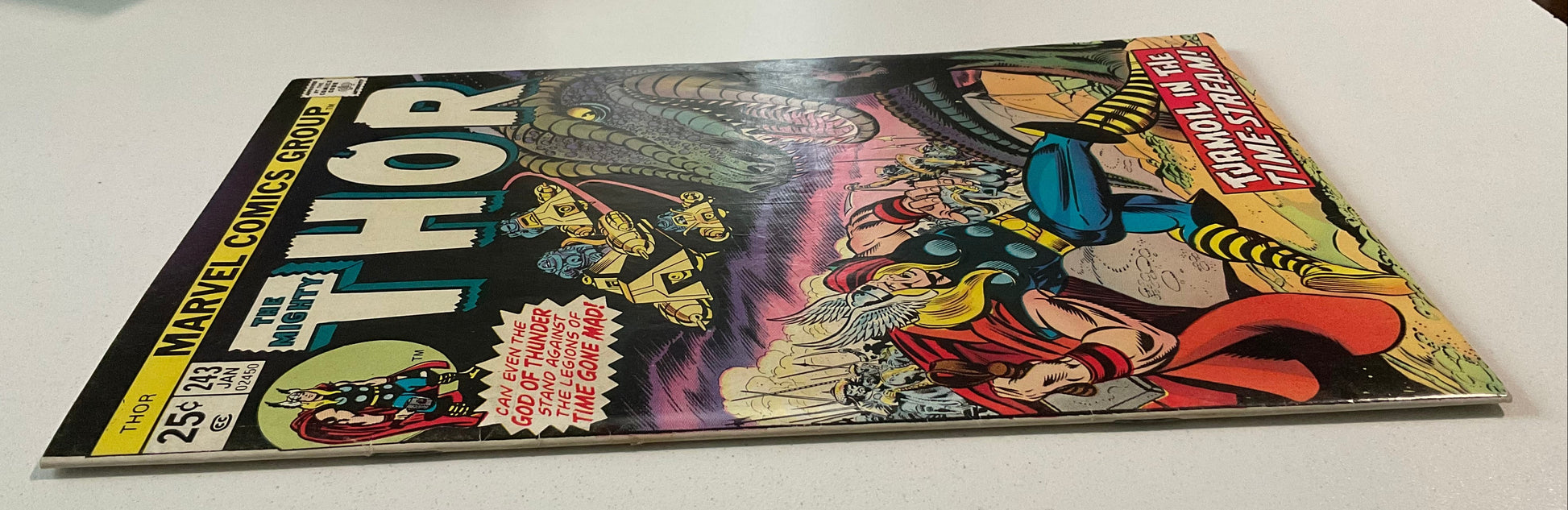 Comic book featuring Thor on a white surface with stacks of paper in the background