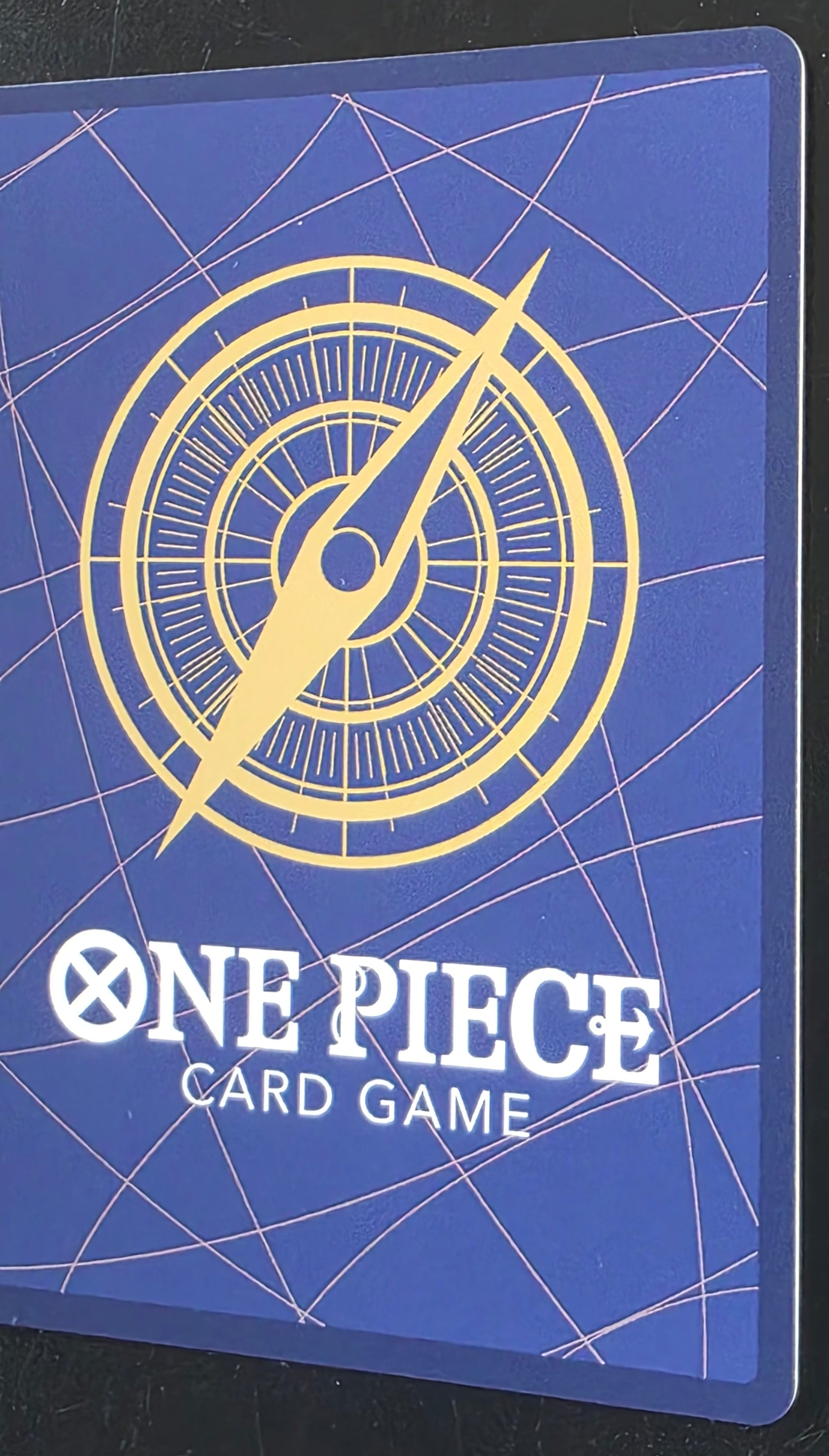Blue card with yellow compass design and 'One Piece Card Game' text on a black background