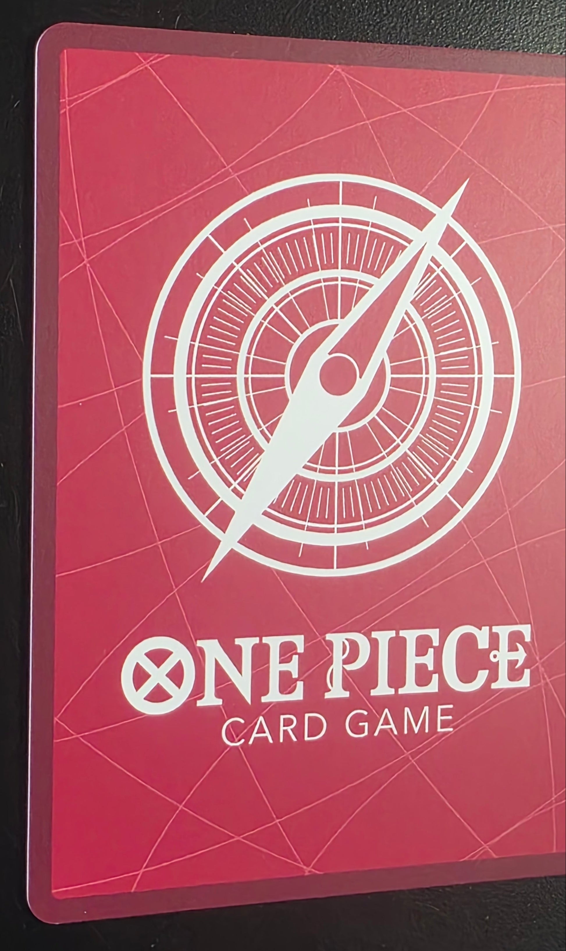 Red card game mat with compass design and 'One Piece' text on a black background